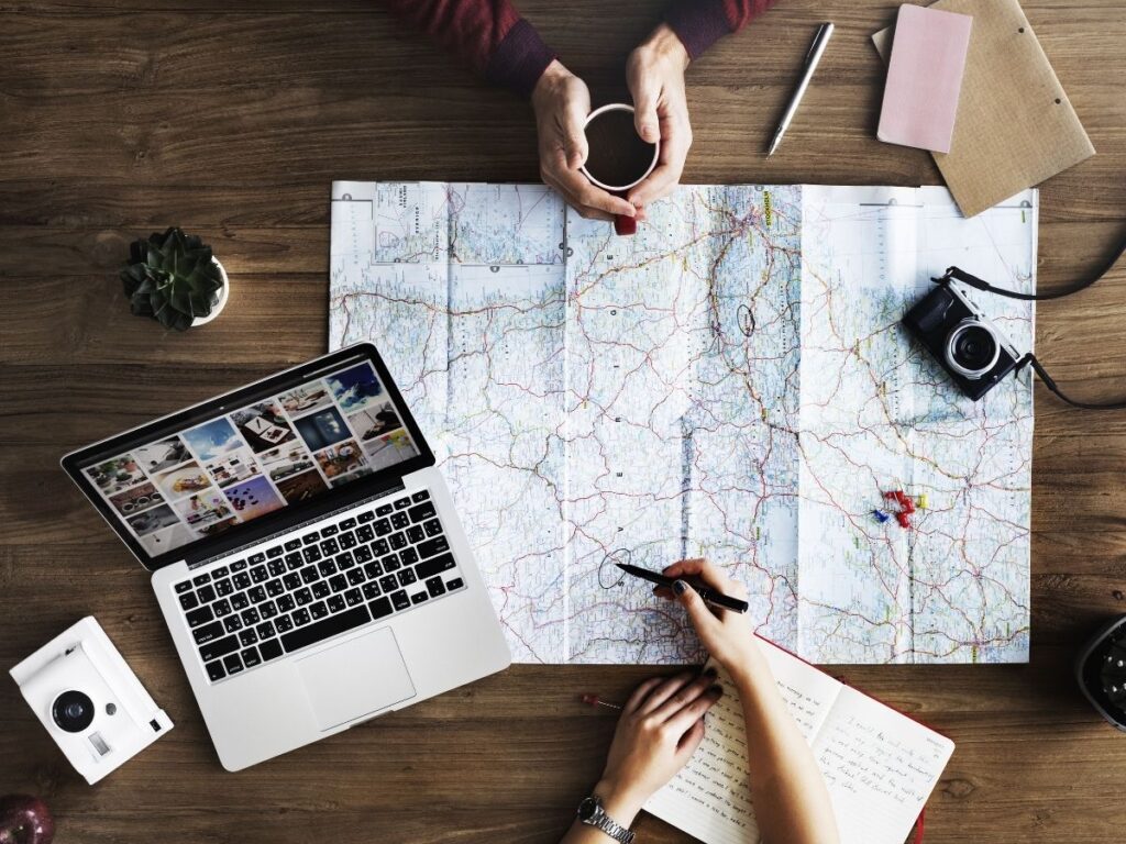 Laptop and travel map on desk, symbolizing remote work and trip planning