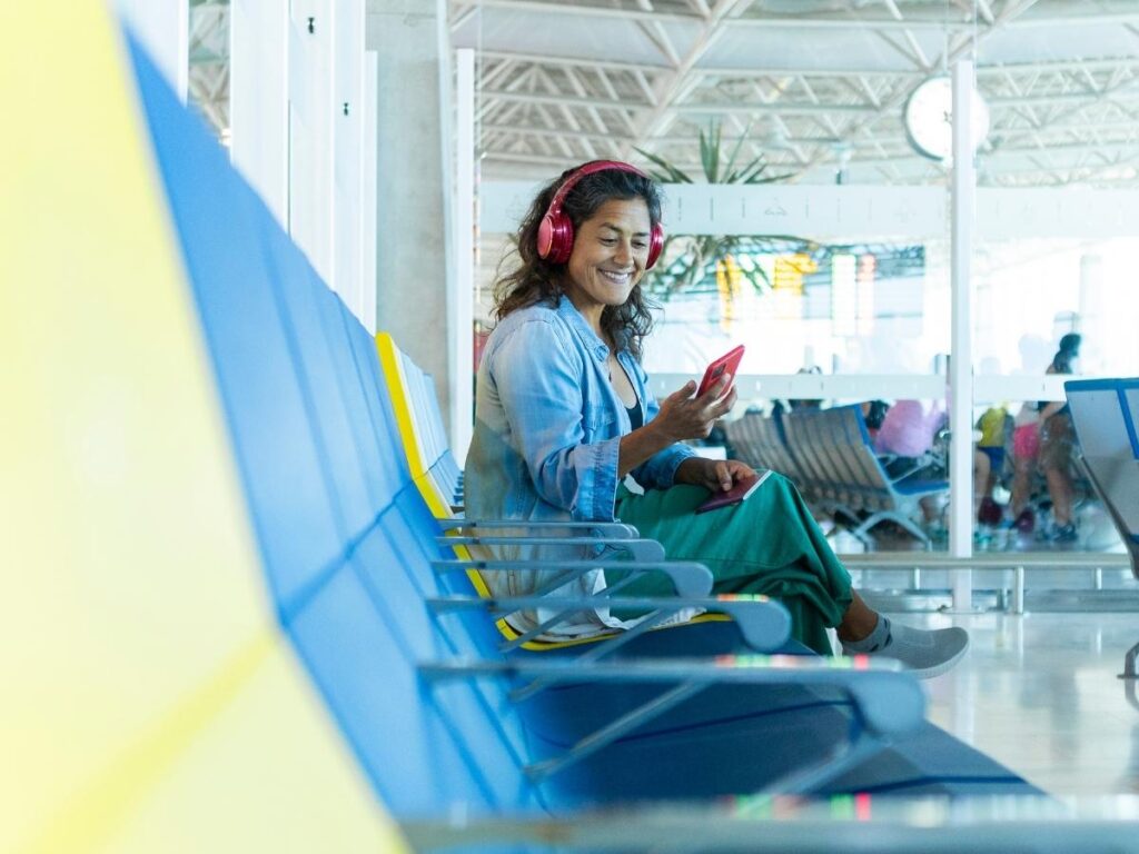 Traveler listening to music on headphone on an airport.