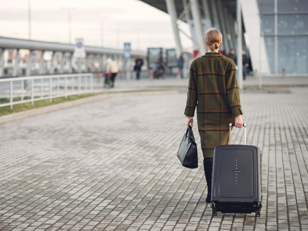 Person walking through an airport terminal with a small carry-on and crossbody bag
