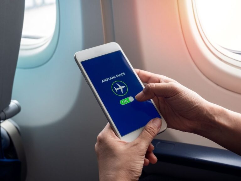 Traveler turning on airplane mode on phone before takeoff