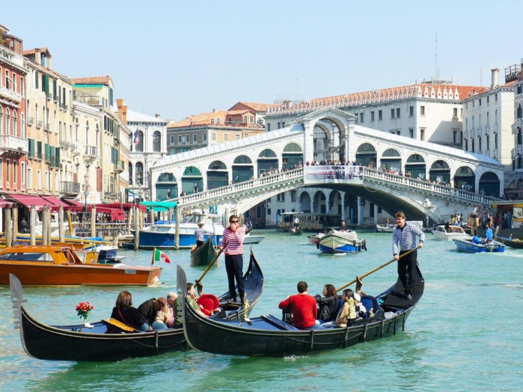 A small traghetto gondola ferry crossing a quiet Venetian canal with locals on board.
