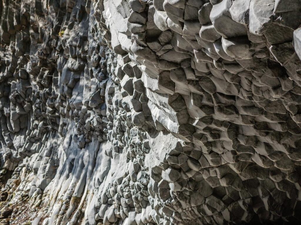 Visitors wading through the icy river at the Alcantara Gorges, surrounded by towering basalt walls