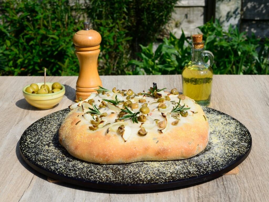 Burrata cheese, focaccia barese with tomatoes, and taralli on a rustic table.