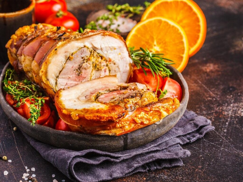 Slices of herb-roasted porchetta on a wooden cutting board in Ariccia"