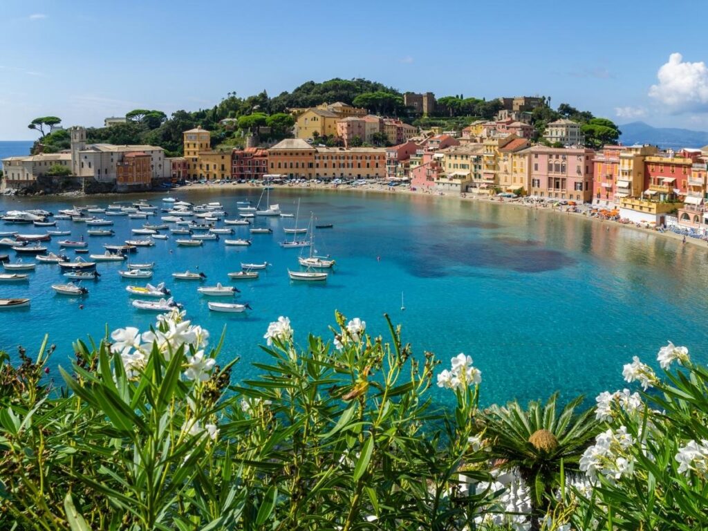 Calm evening at Baia del Silenzio in Sestri Levante with beachgoers and pastel houses by the water.