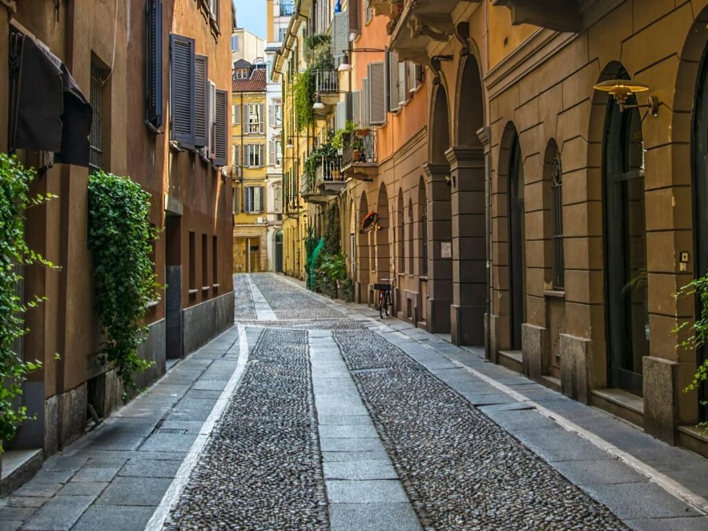 Cobblestone lane in Brera with an outdoor café and warm evening lights.