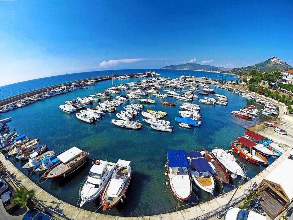 Ferry boat departing from Salerno harbor with Amalfi Coast cliffs in the background.