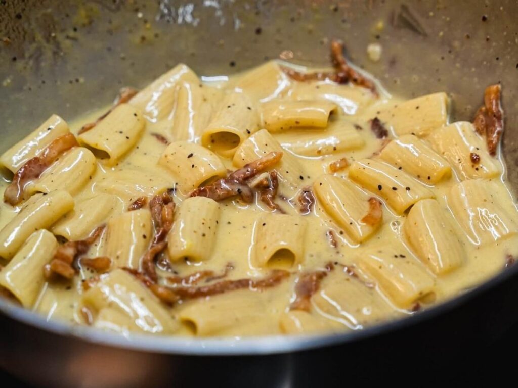 Plate of creamy carbonara pasta topped with pecorino cheese