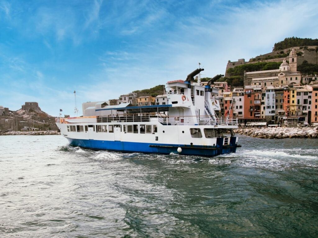 Ferry approaching the Cinque Terre coastline with villages on the cliffs.