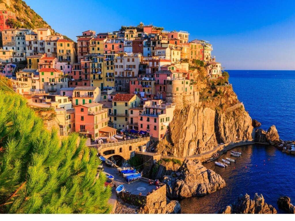 Vernazza harbor at sunset with fishing boats and warm light on the buildings.
