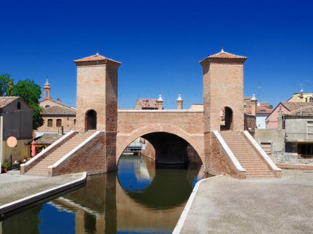 Pastel houses and arched bridges reflected in the canals of Comacchio