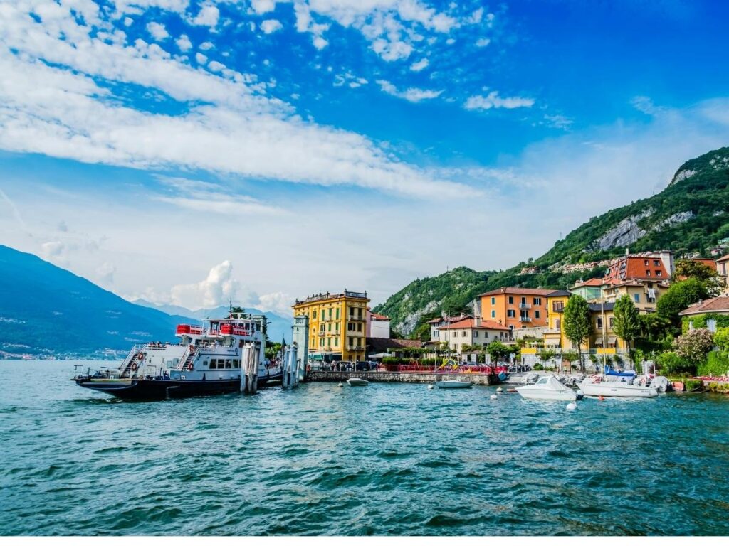 Ferry crossing Lake Como with passengers on deck and villas along the shore.