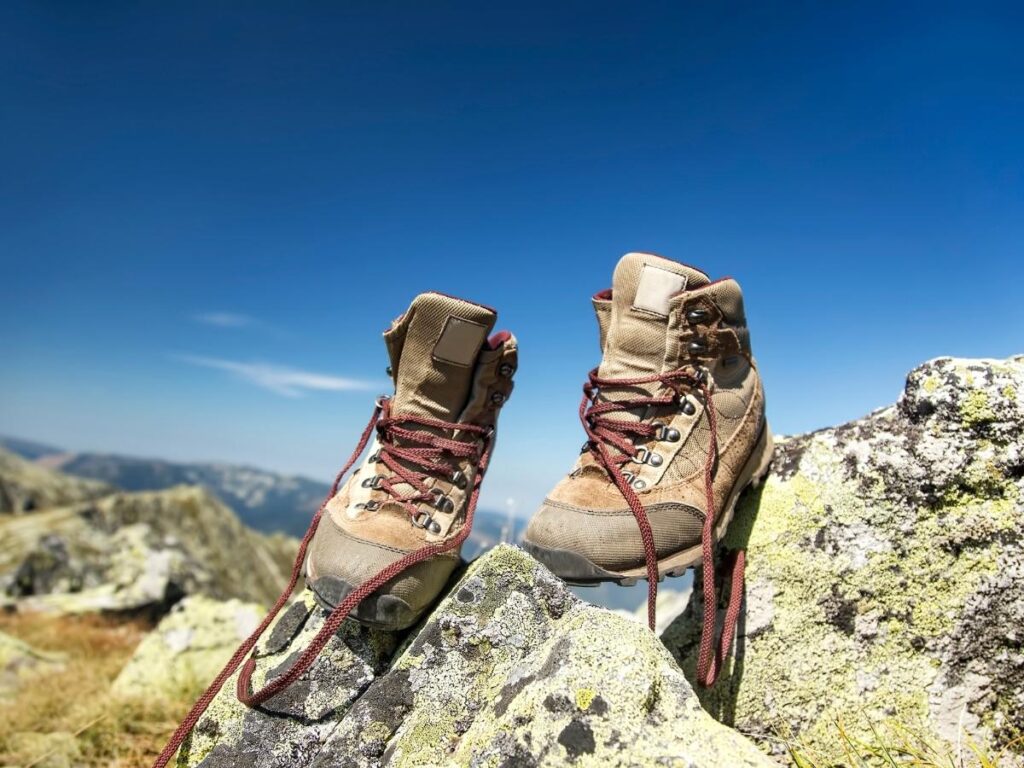 Hiking boots standing on uneven volcanic rock and ash on Etna’s trails.