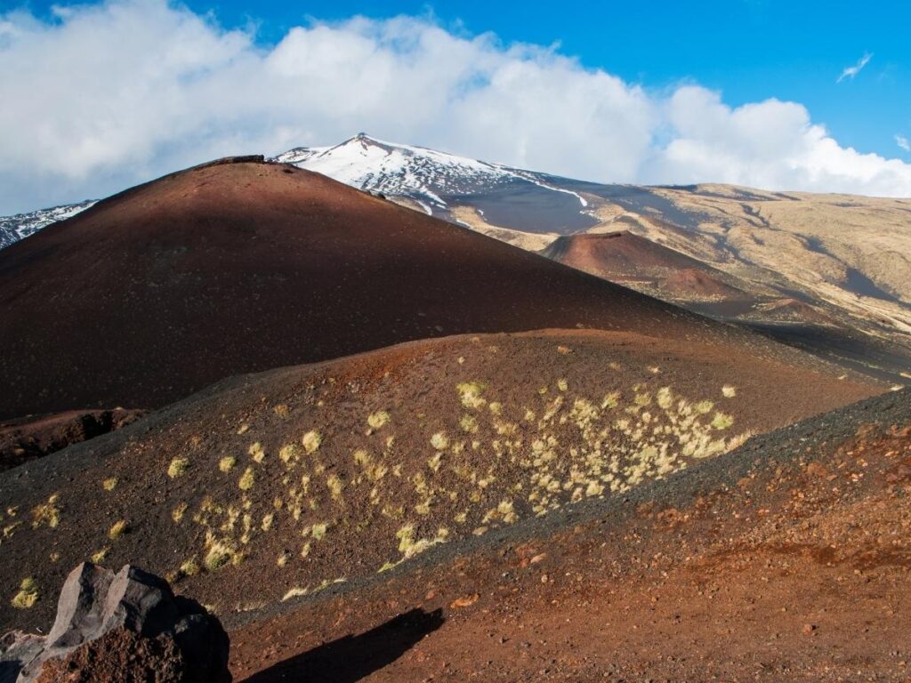 Golden sunset light over Mount Etna’s craters, with faint lava glow visible in the darkening sky.”