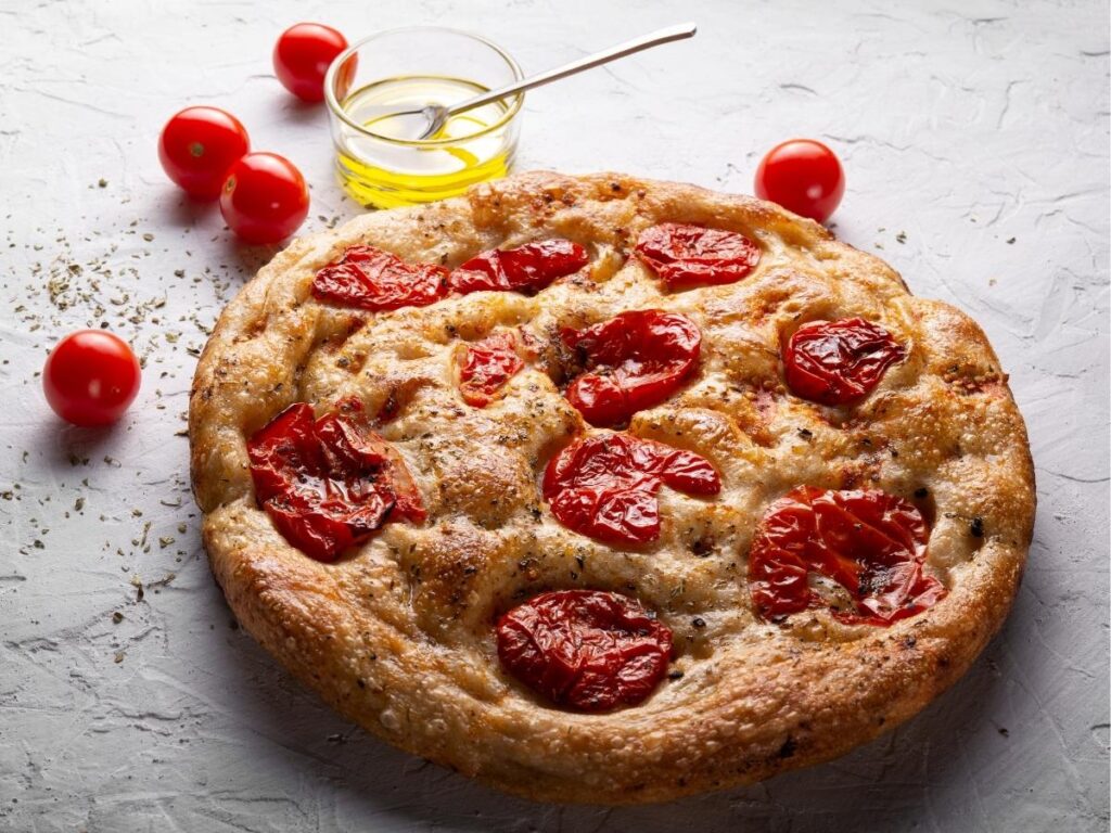 Focaccia barese topped with cherry tomatoes and olives, fresh from the oven.