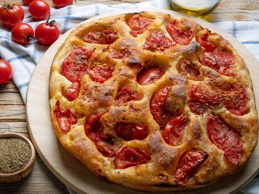 Slice of focaccia Barese with cherry tomatoes and olive oil.
