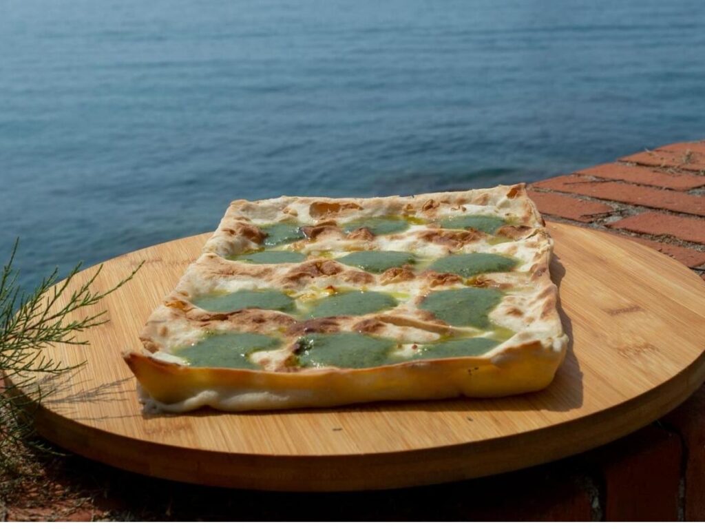 Thin focaccia di Recco with melted cheese filling, fresh from a Ligurian bakery oven.