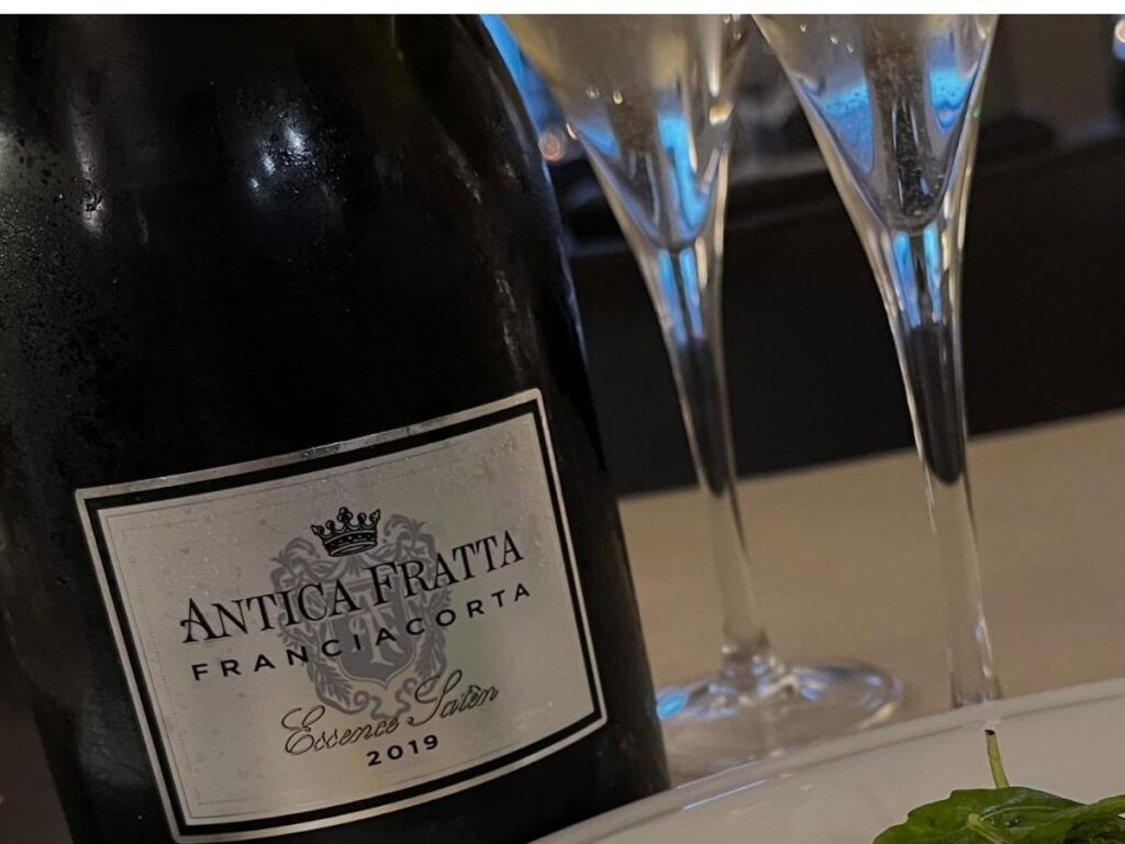 Small Franciacorta vineyard tasting with glasses of sparkling wine on a wooden table.