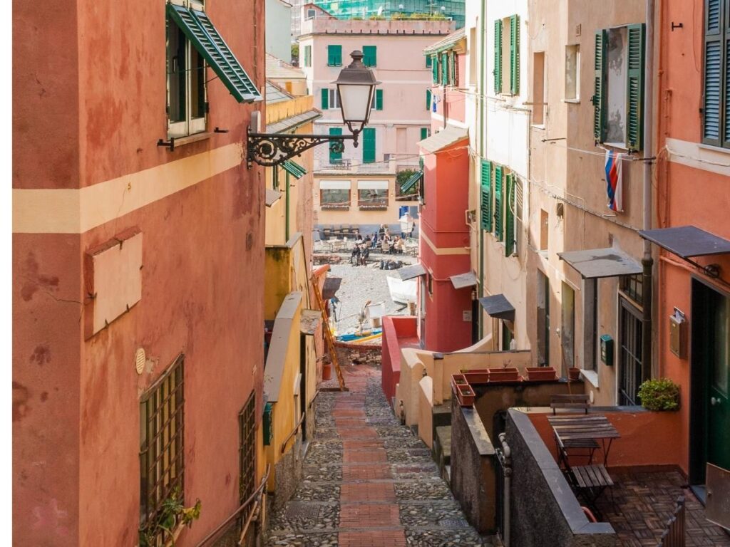 Narrow alleyway in Genoa’s historic center with tall pastel buildings and laundry strung between windows.