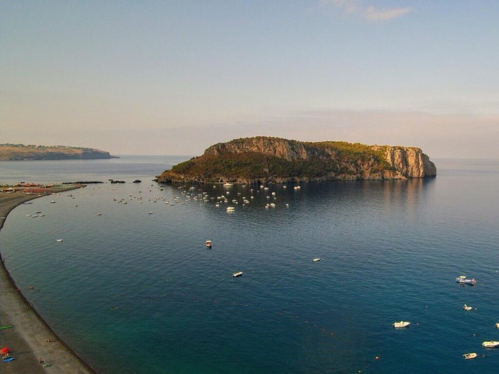 Small boat entering a blue-lit sea cave at Isola di Dino, Calabria