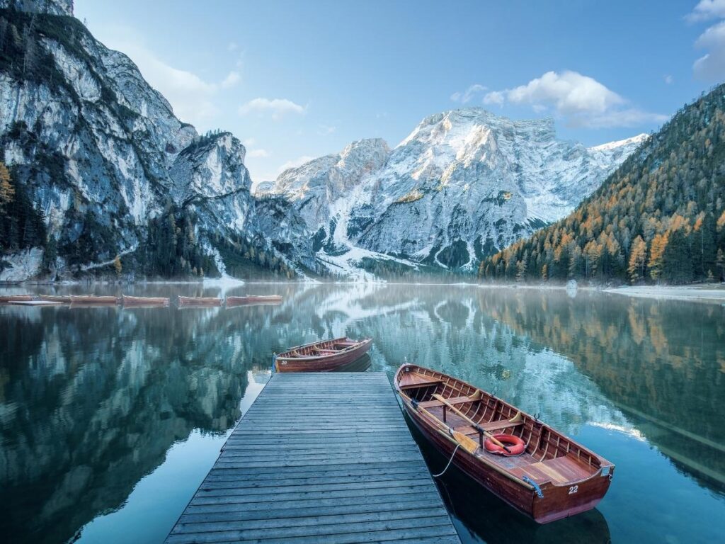 Wooden boats on the emerald water of Lago di Braies at sunrise in the Dolomites, Italy.