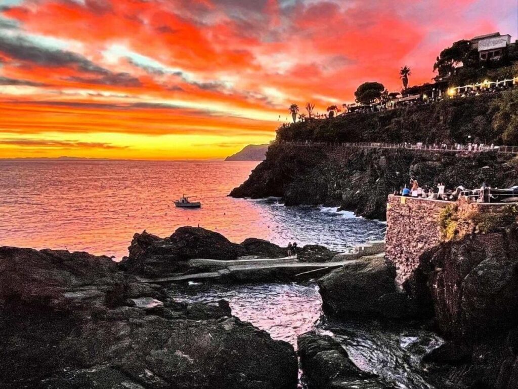 Manarola village perched on cliffs with pastel houses glowing at sunset above the sea.