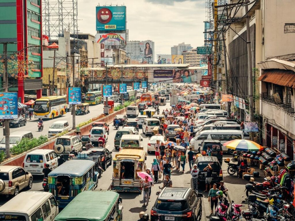 Busy street in Manila with jeepneys, street vendors, and no sidewalks