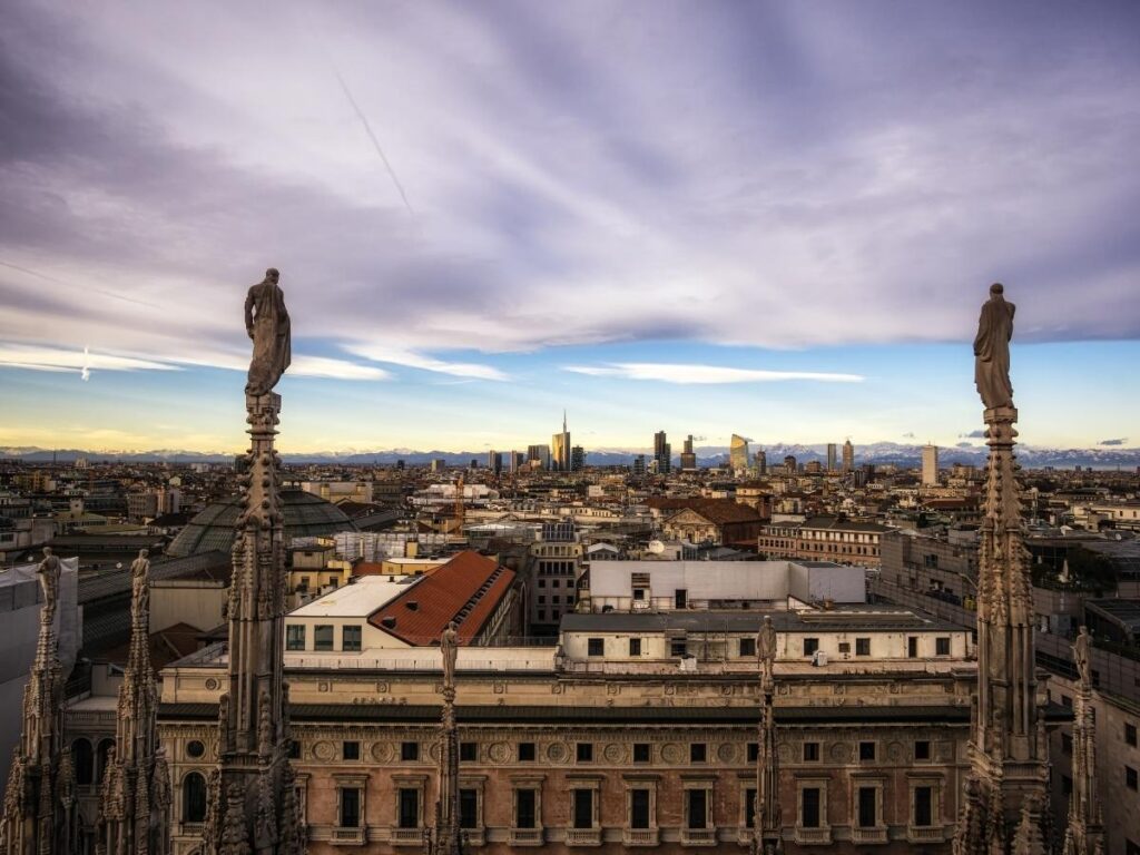 Visitors on the Duomo rooftop looking across Milan’s skyline at sunrise.