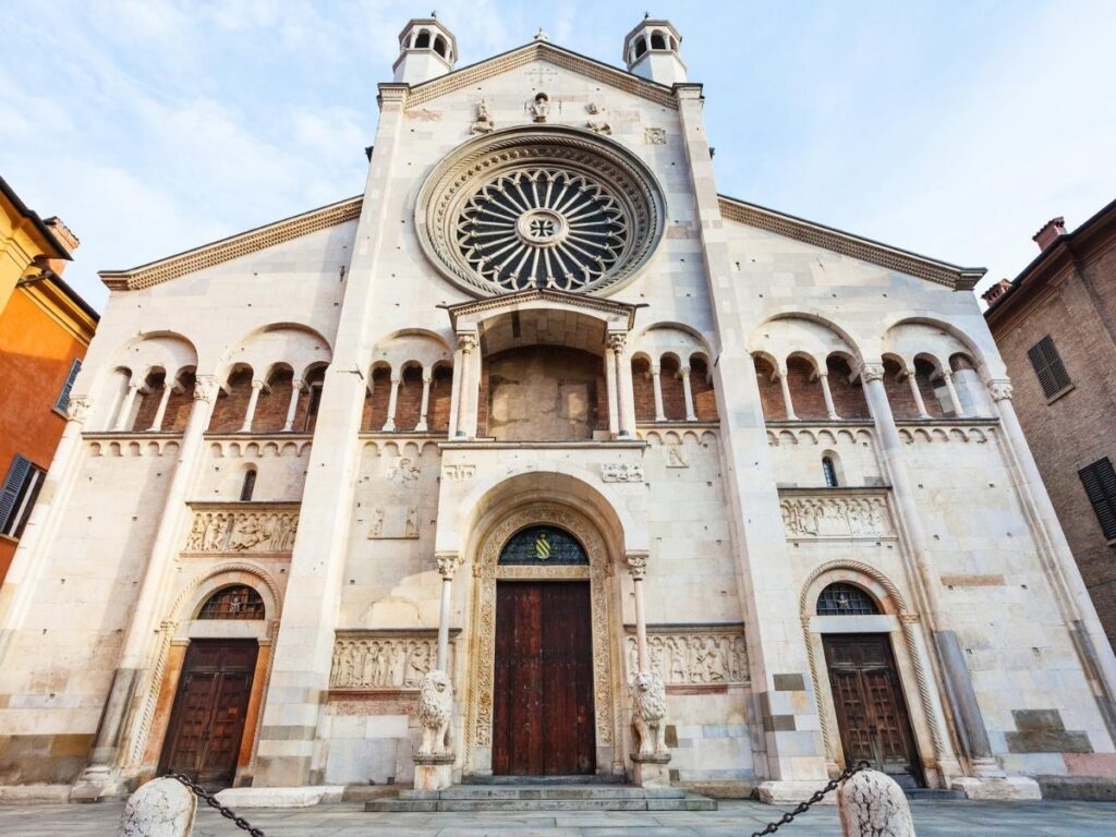 The stone façade of Modena Cathedral with sculpted lions and Romanesque carvings
