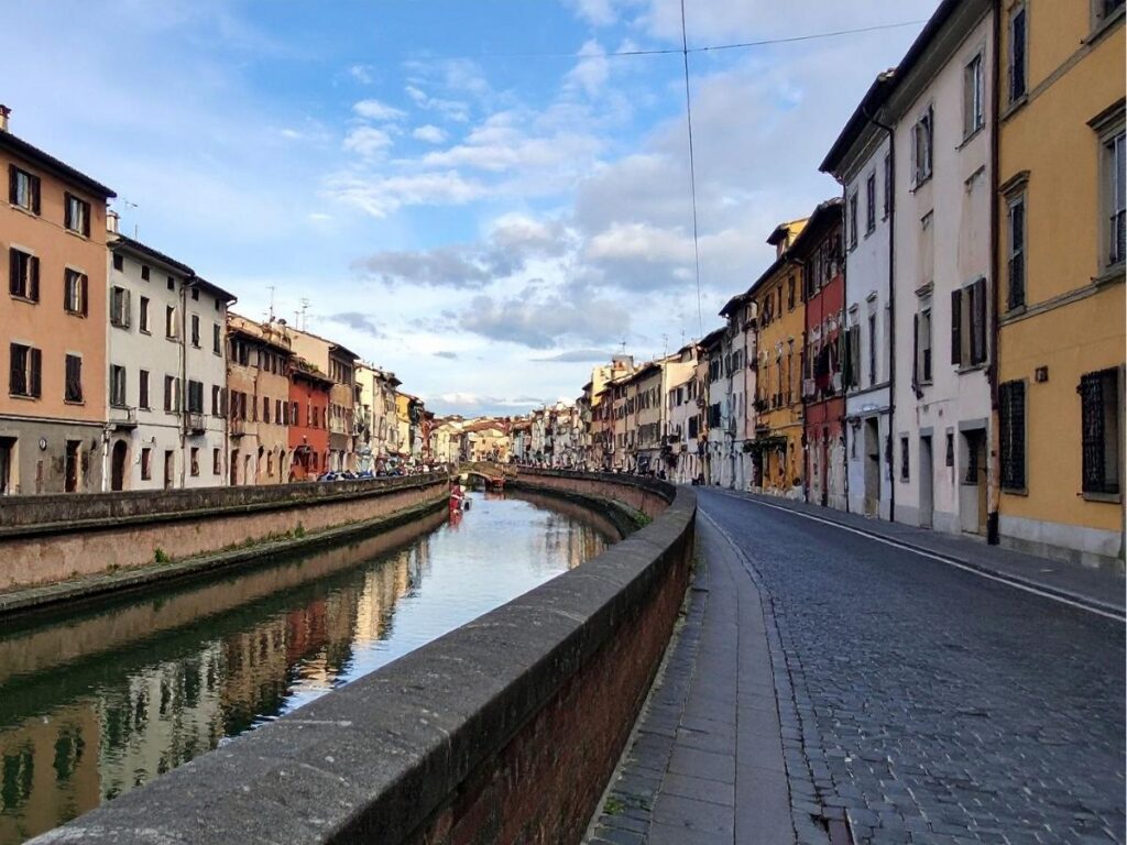 A quiet cobblestone alley in Modena with ivy-covered buildings