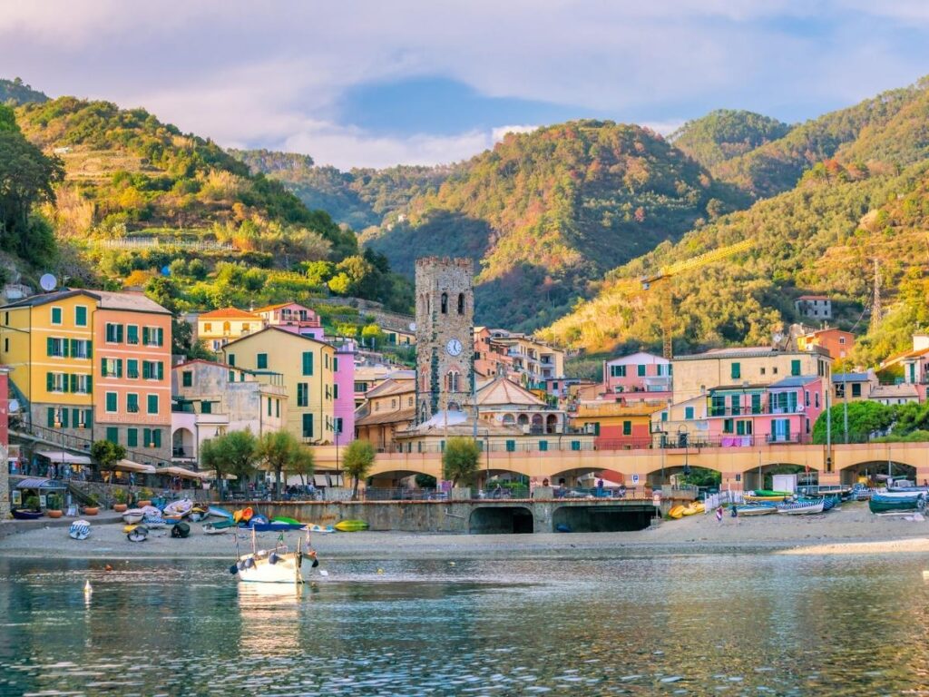 Wide sandy beach at Monterosso al Mare with colorful umbrellas and turquoise waves.