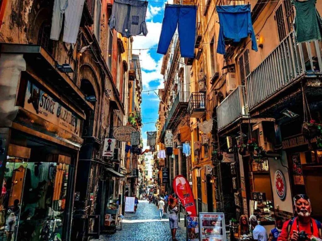 Bustling Spaccanapoli street in Naples with scooters and laundry hanging above.
