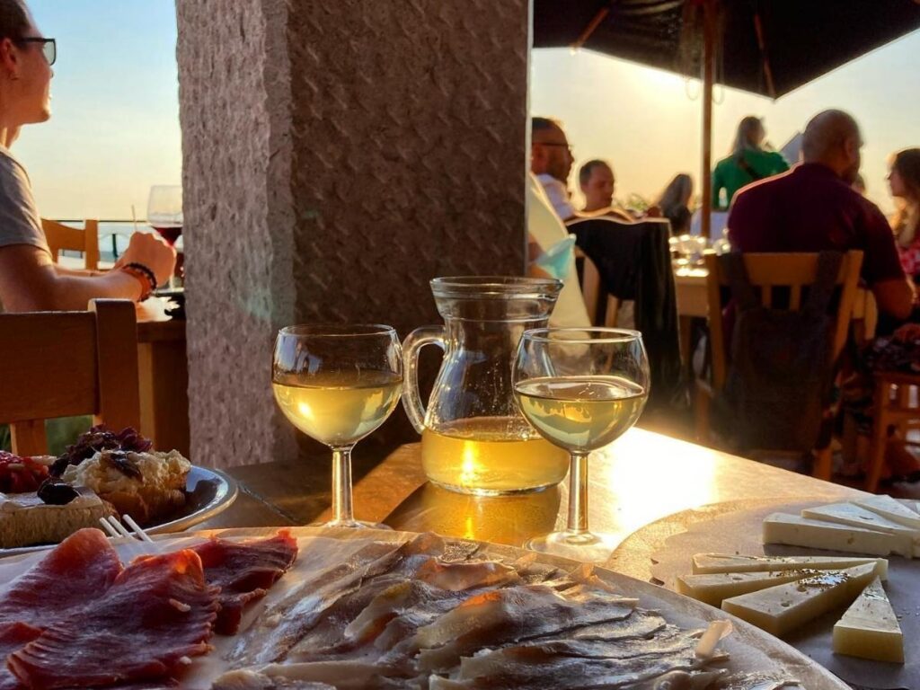 Long wooden table inside an osmiza with locals sharing plates of salumi and wine.