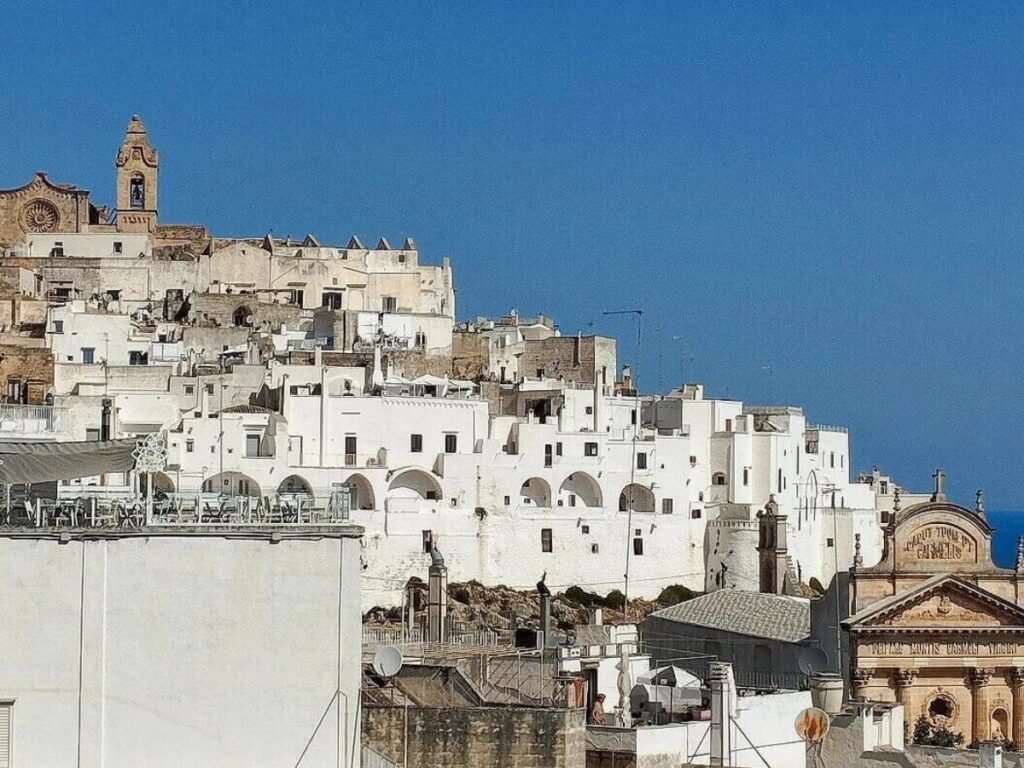 Sunset view of Ostuni’s white city skyline from a rooftop bar.