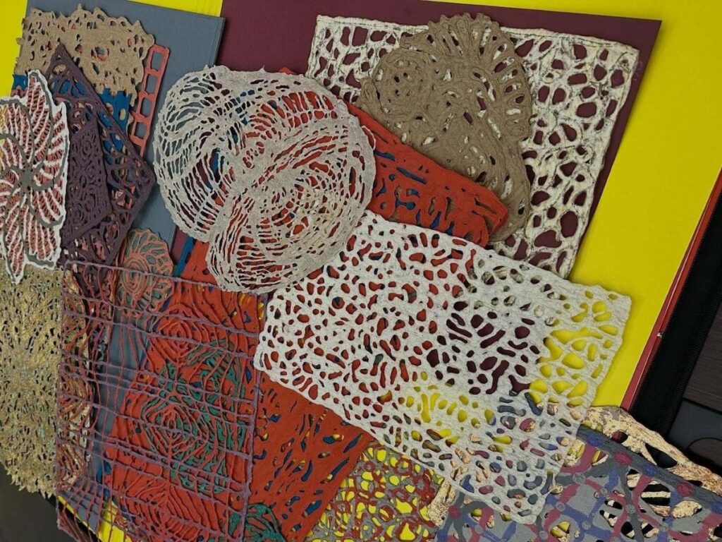 Hands at work pressing handmade paper sheets in a traditional workshop near Brescia.