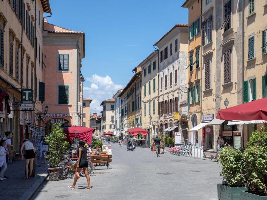 Arcade-lined Borgo Stretto street in Pisa with cafés and boutiques.