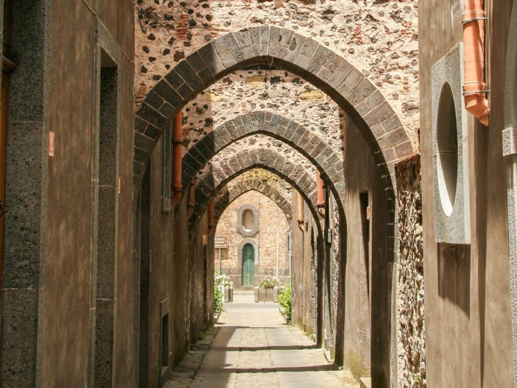 Street scene in Randazzo with medieval lava-stone buildings and a café serving pistachio granita.