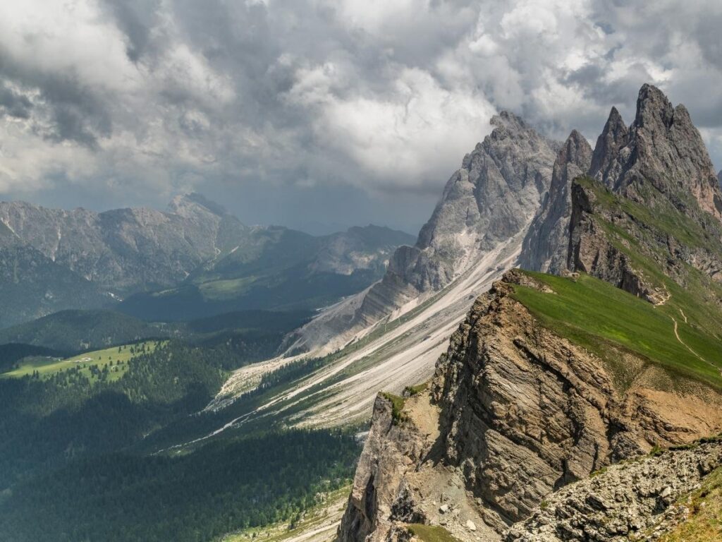 Jagged Seceda ridgeline in Val Gardena with wildflowers and paragliders soaring above the Dolomites.