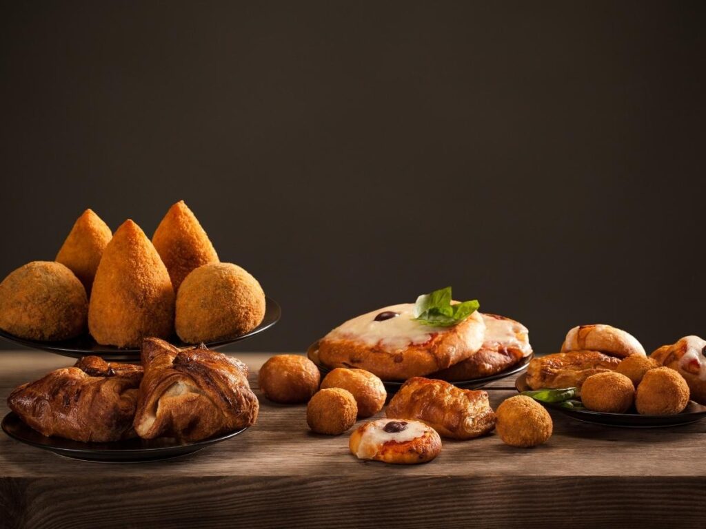 Golden fried arancini rice balls stacked high at a Palermo street food stall.”