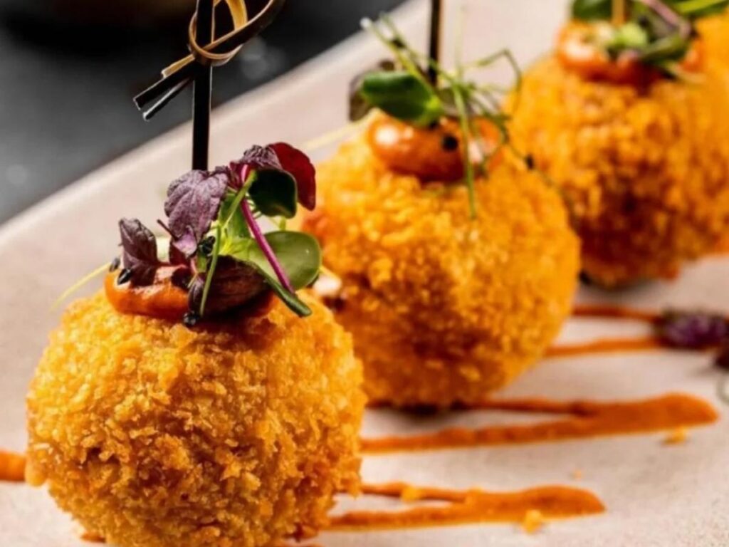 Close-up of a vendor handing over a hot arancini from a Palermo street food stall.