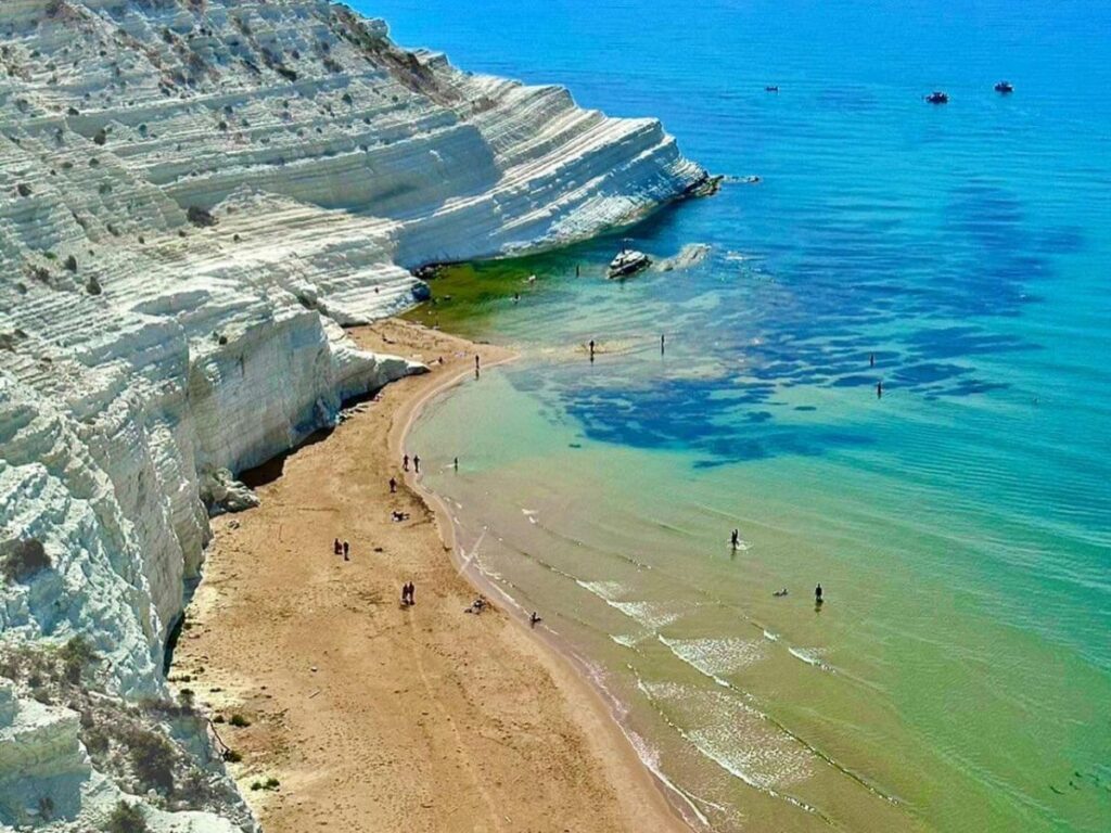 White terraced limestone cliffs of Scala dei Turchi meeting the deep blue Mediterranean sea.
