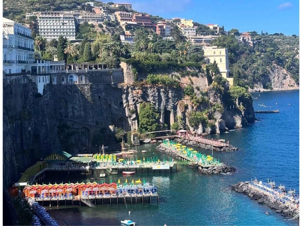 Marina in Sorrento with fishing boats and cliffs rising behind.