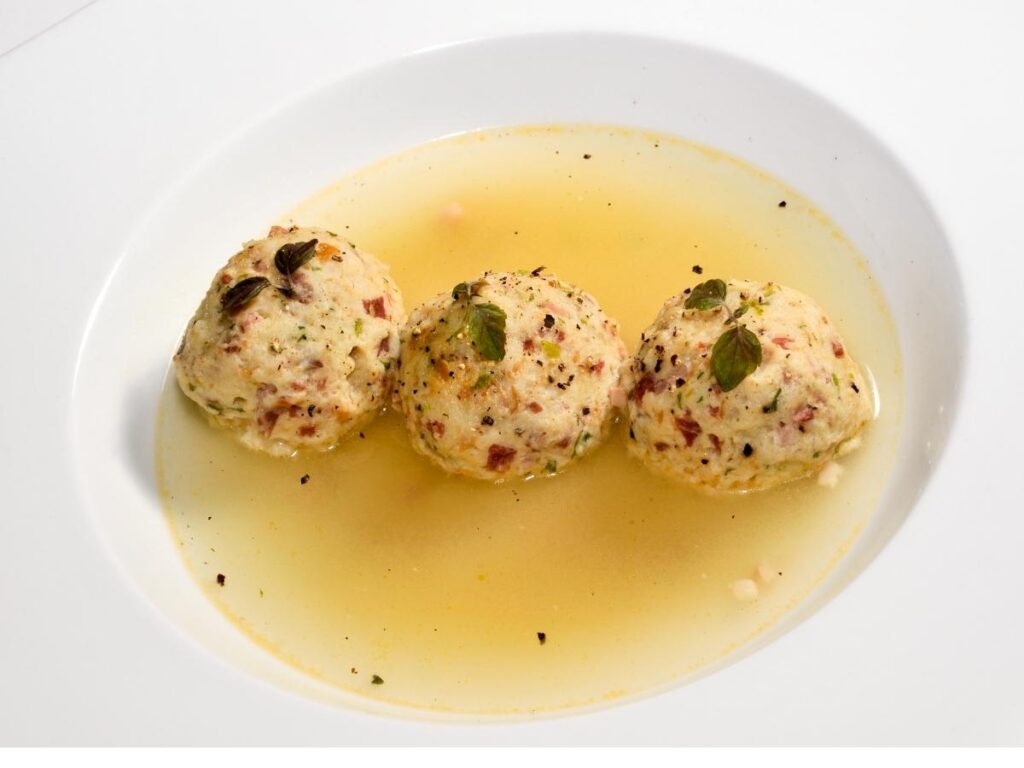 Close-up of a rustic plate of canederli dumplings with speck and mountain cheese.