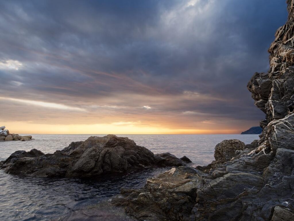 People picnicking on the rocks in Manarola watching the sunset over the village.