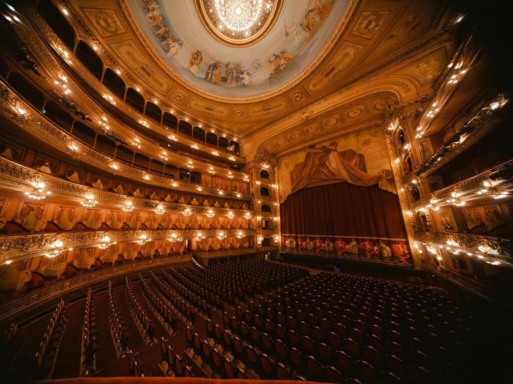 Interior view of Teatro alla Scala with red velvet seats and gilded balconies.