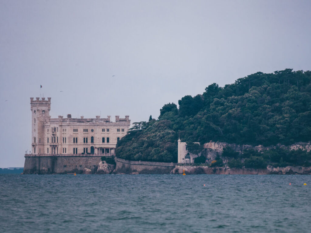 Miramare Castle perched on rocky cliffs with the Adriatic Sea below.