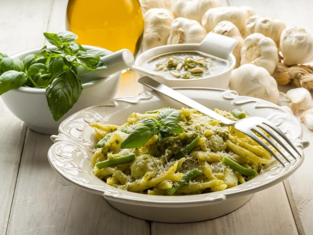 Traditional trofie pasta with fresh Genovese pesto and basil served in a rustic bowl.