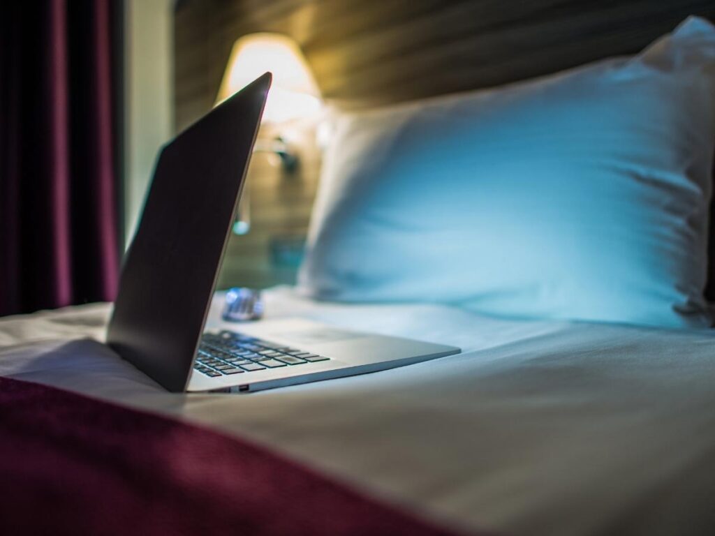 Laptop untouched on hotel bed, showing unnecessary tech packing