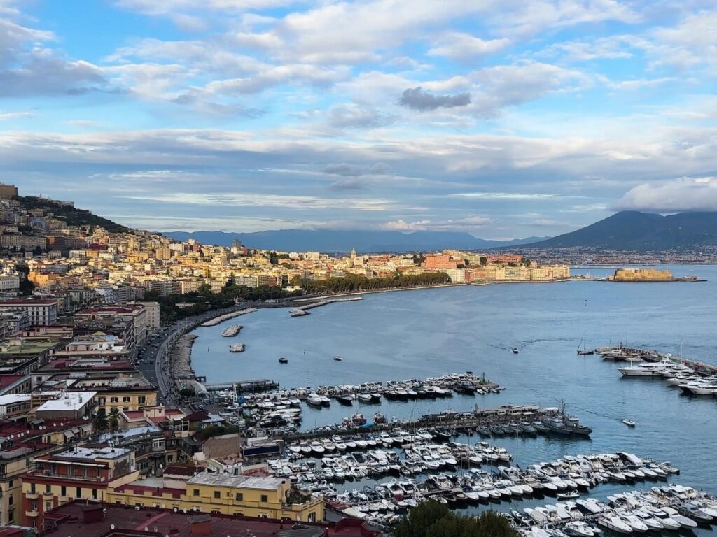 Visitors standing on the rim of Mount Vesuvius crater with sweeping views of Naples Bay.
