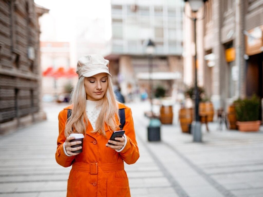 Woman walking through a European city looking at Google Maps on her phone for walking directions